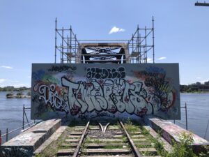 Railroad bridge blocked off by barrier covered in graffiti